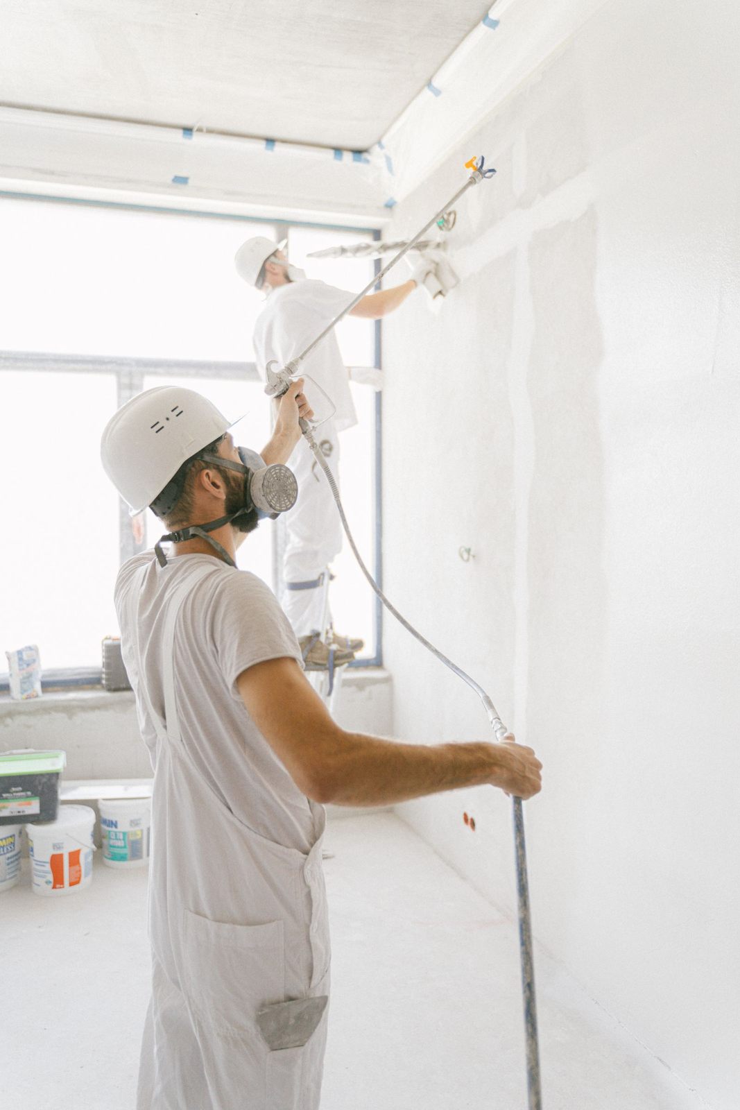 Two professional painters working indoors on wall renovation and painting project